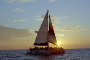 Island Time sailing catamaran with guests silhouetted against sunset